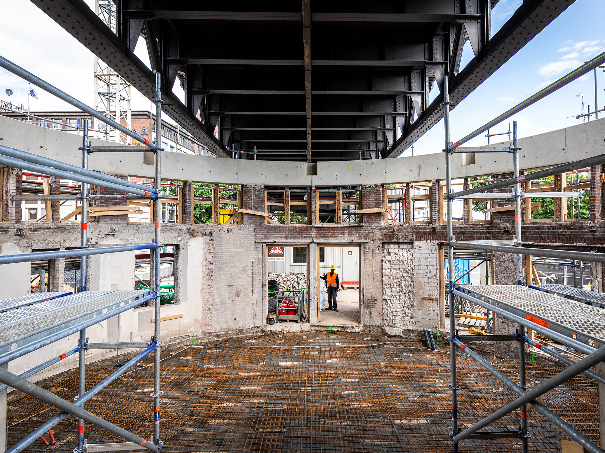Eine Baustelle einer Schalterhalle im Rohbau. Darüber läuft eine U-Bahn-Trasse