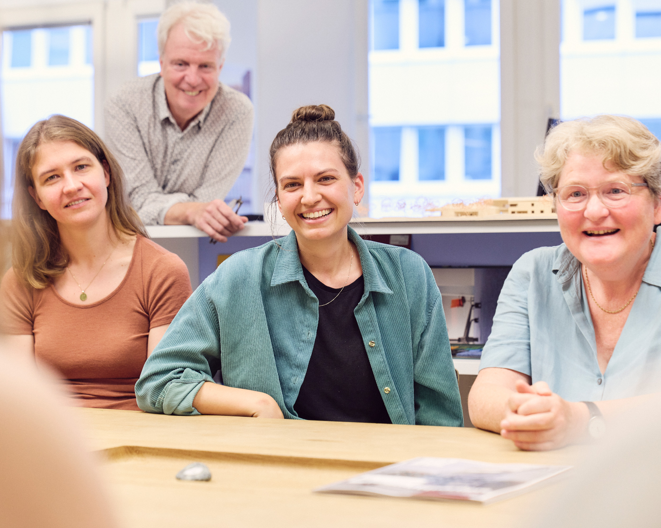 Fröhliche Menschen an einem Besprechungstisch bei Trapez Architektur