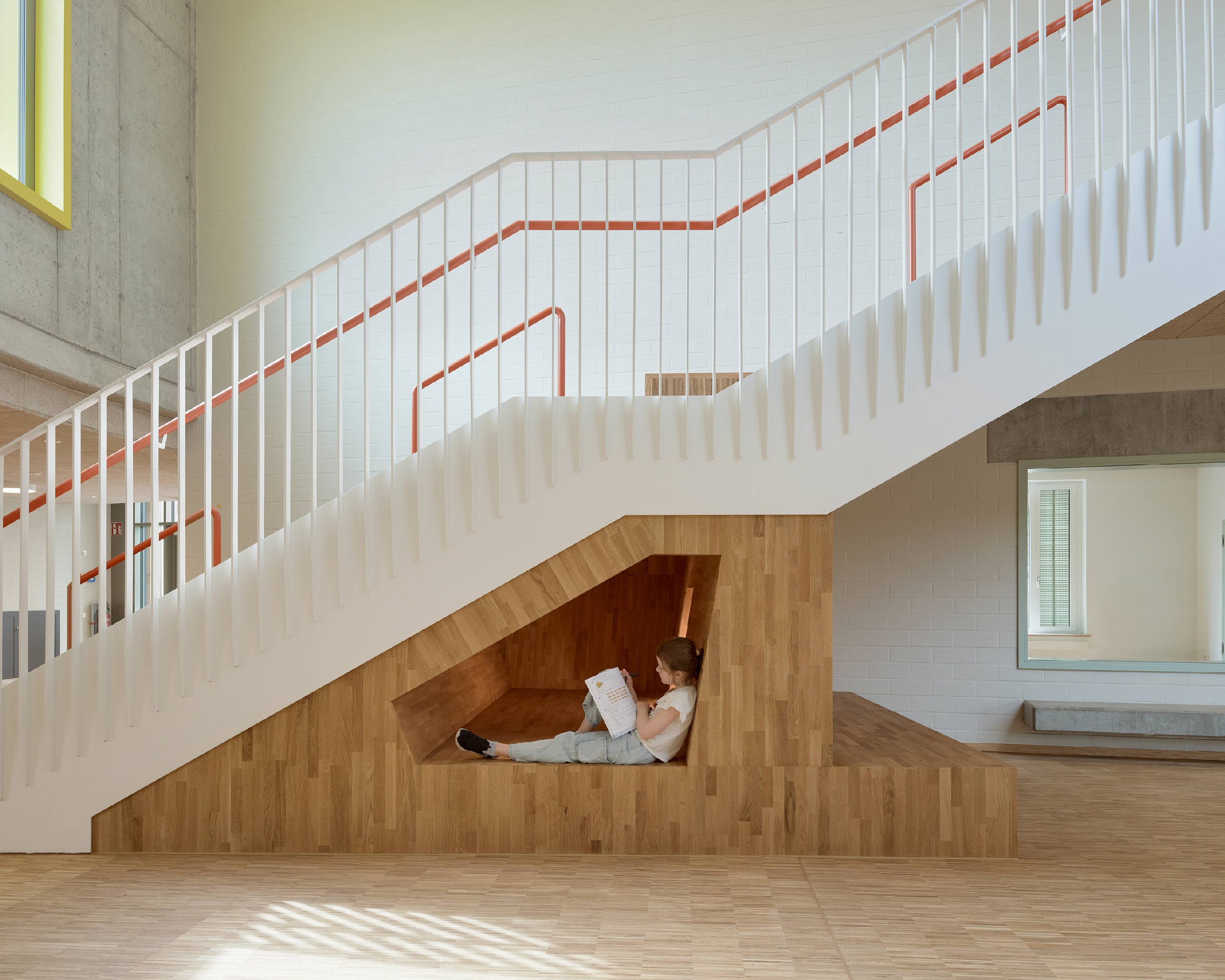 Lesendes Kind sitzt in einem Einbaumöbel mit Nische, das sich unter einer Treppe befindet