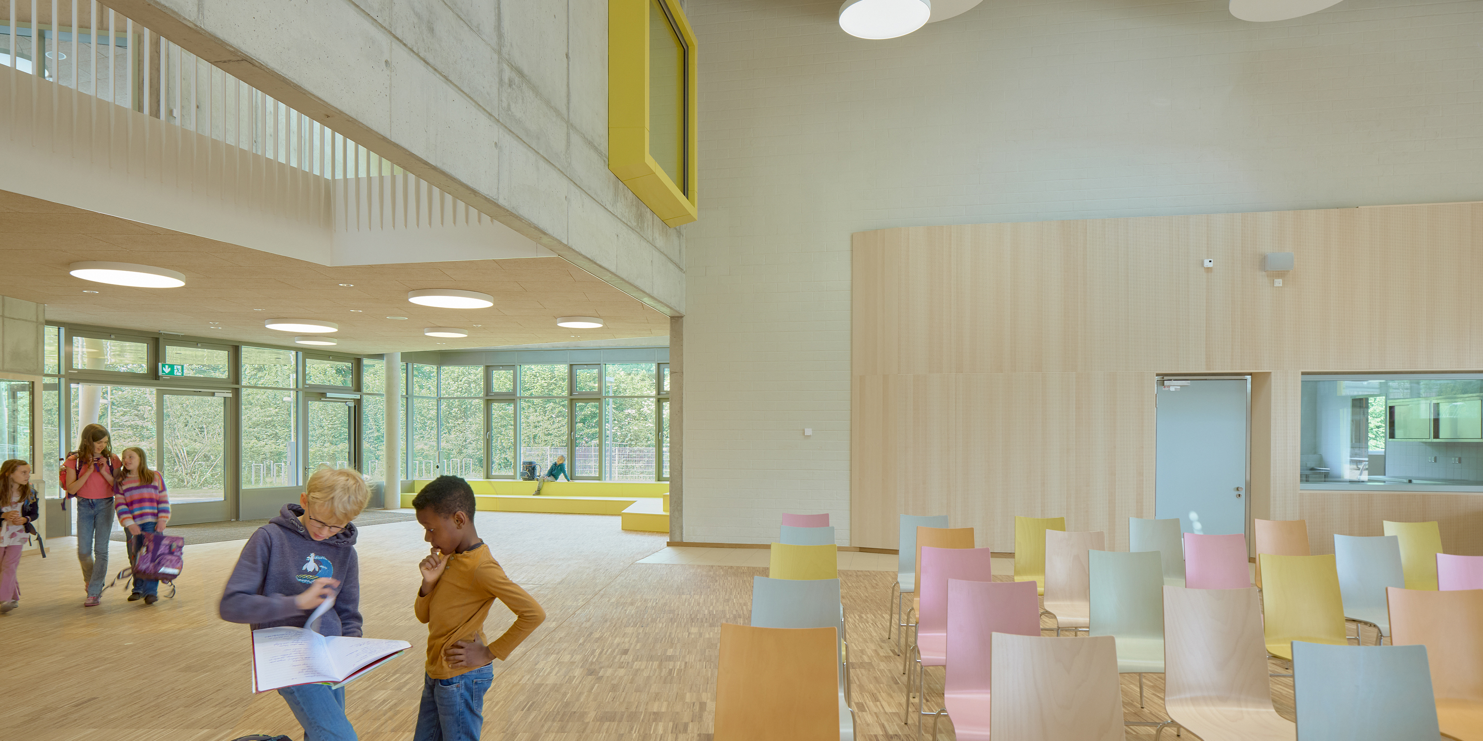 Kinder im Eingangsbereich einer Schule mit bunt bestuhltem Foyer