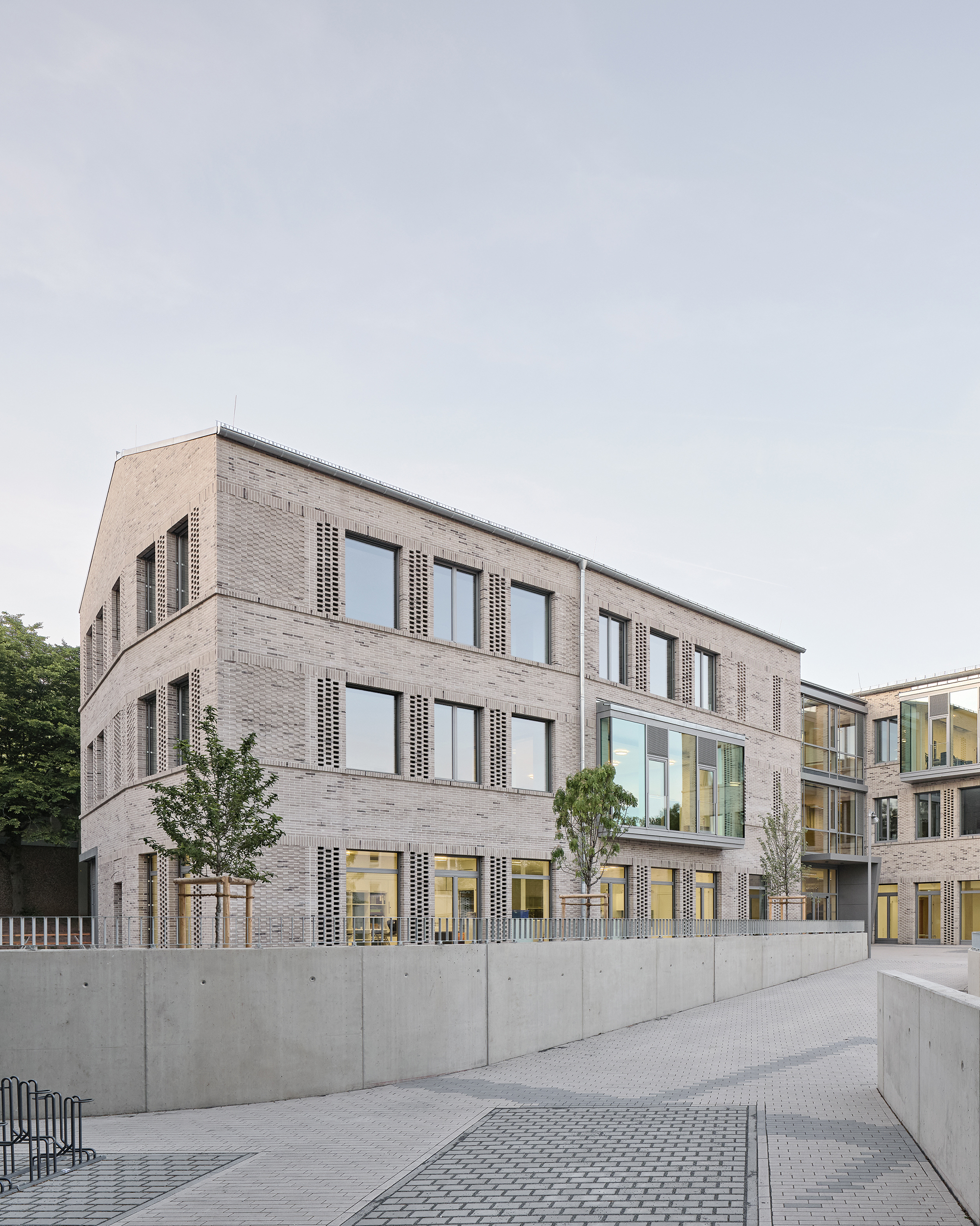 Zwei Flügel eines Schulgebäudes mit heller klinkerfassade und großen Fenstern