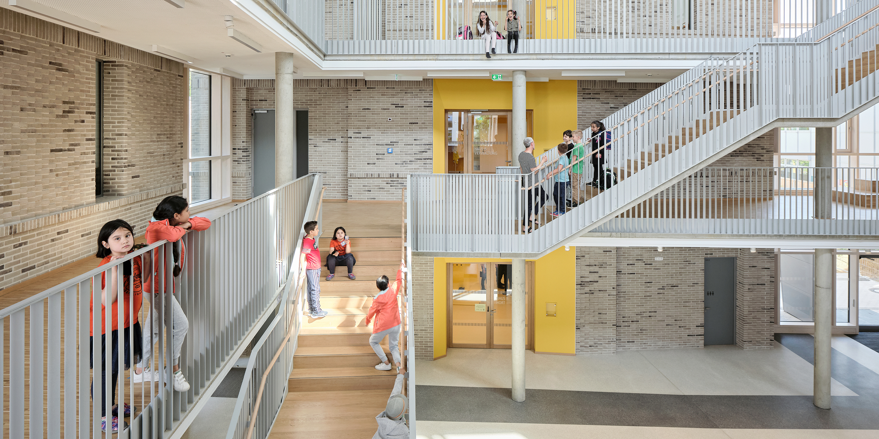 Kinder auf einer Treppe und umlaufenden Galerien  im Atrium einer Schule.